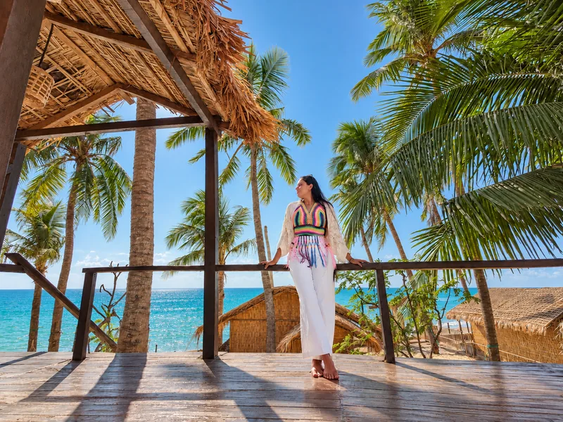 A guest on the sea-view rooftop of Charcoal Restaurant at Dwipantor, surrounded by coconut palms