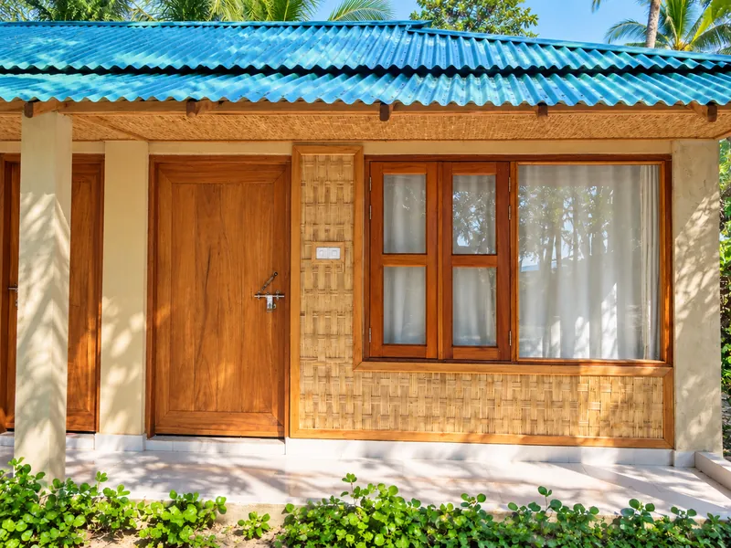 Wooden door, bamboo facade and blue-green roof of a Studio Couple Room at Dwipantor