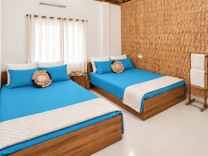 Two wooden beds with turquoise linen and ivory pillows in a Studio Family Room at Dwipantor